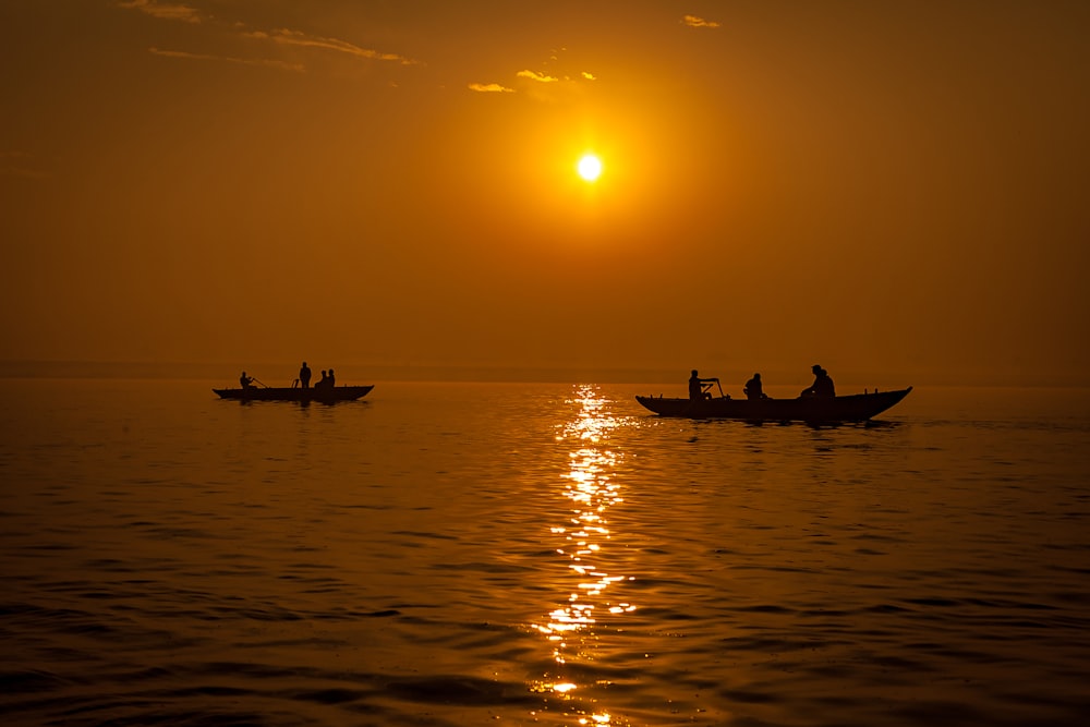 Silhouette von Menschen, die während des Sonnenuntergangs auf dem Boot fahren