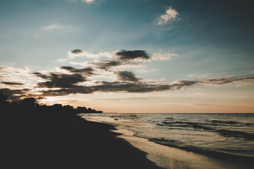 sea waves crashing on shore during sunset