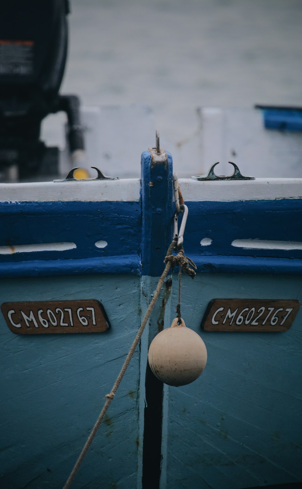 blue and white boat with brown rope