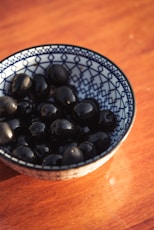 black round fruits on white and blue ceramic bowl