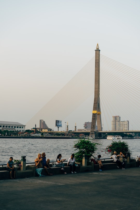 people sitting on bench near body of water during daytime in Rama VIII Bridge Thailand