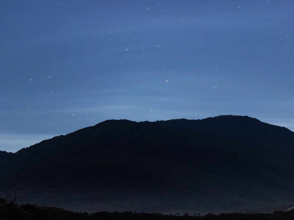 silhouette of mountain under blue sky during night time