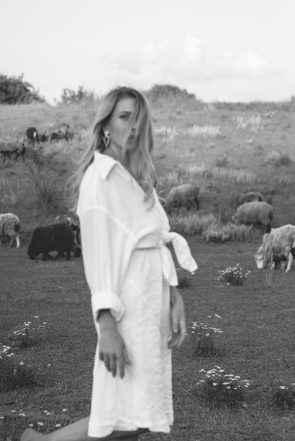 grayscale photo of woman in robe standing on grass field