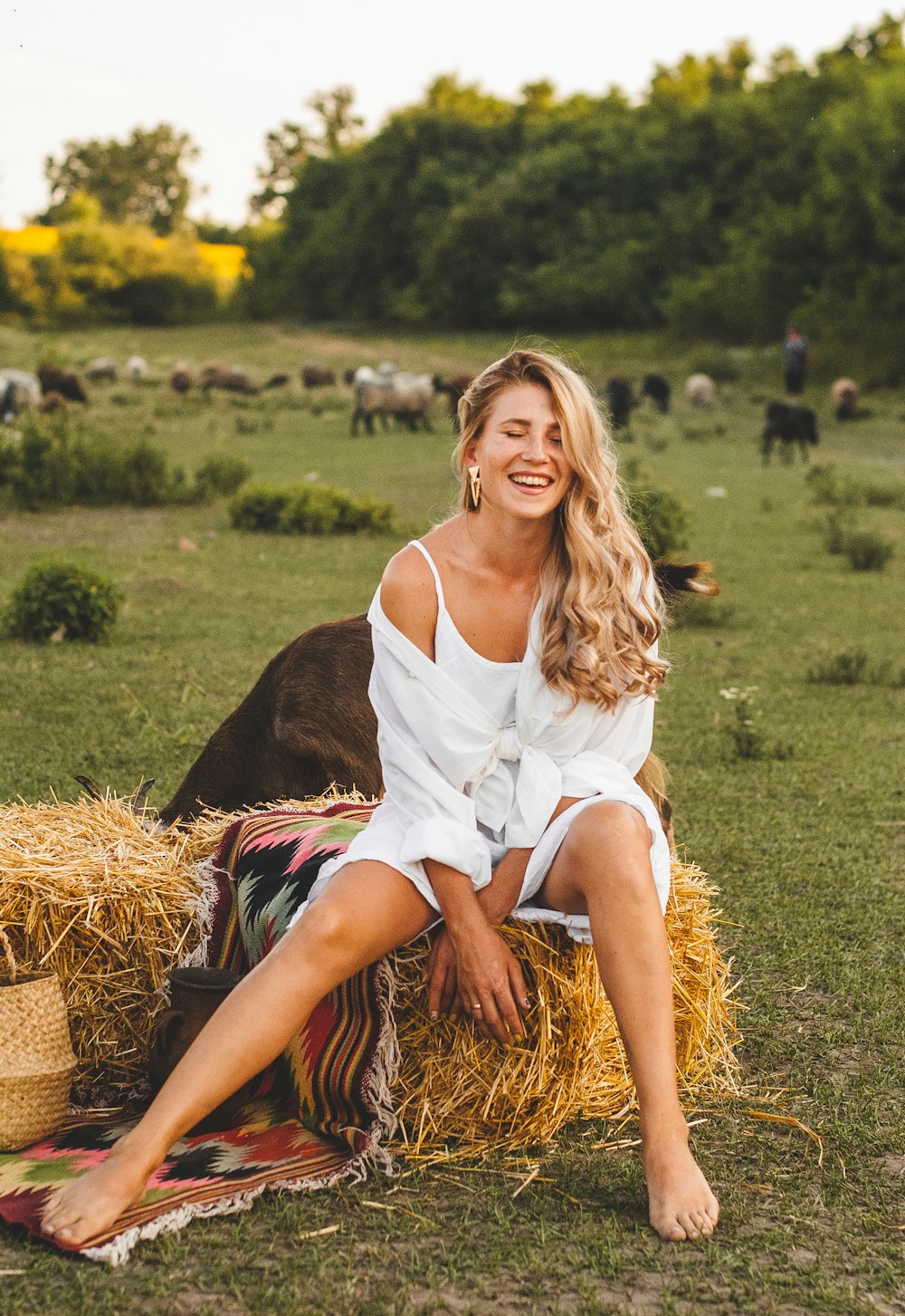 woman in white sleeveless dress sitting on brown grass field during daytime