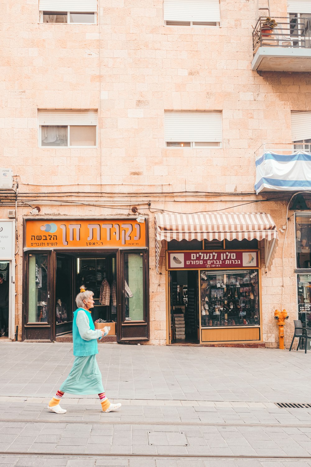 man in blue jacket and blue pants walking on sidewalk near store during daytime