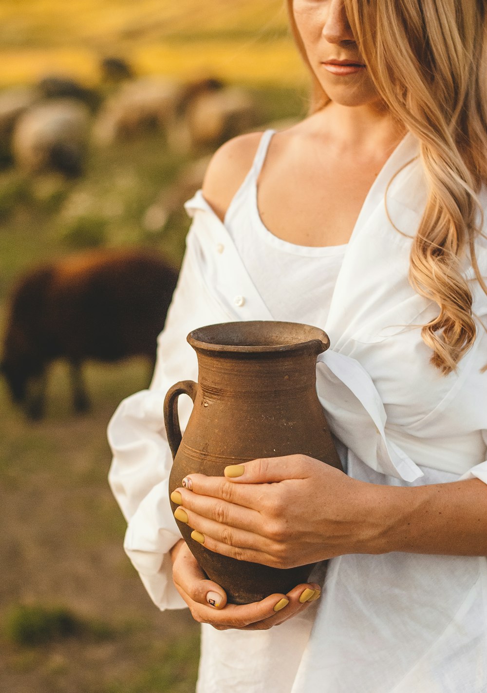 woman in white tank top holding brown ceramic mug