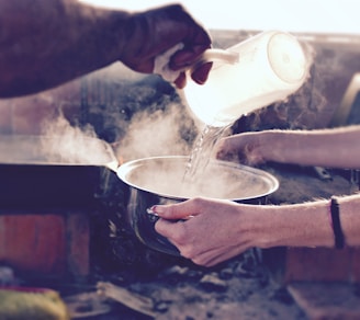 person pouring water on white ceramic mug