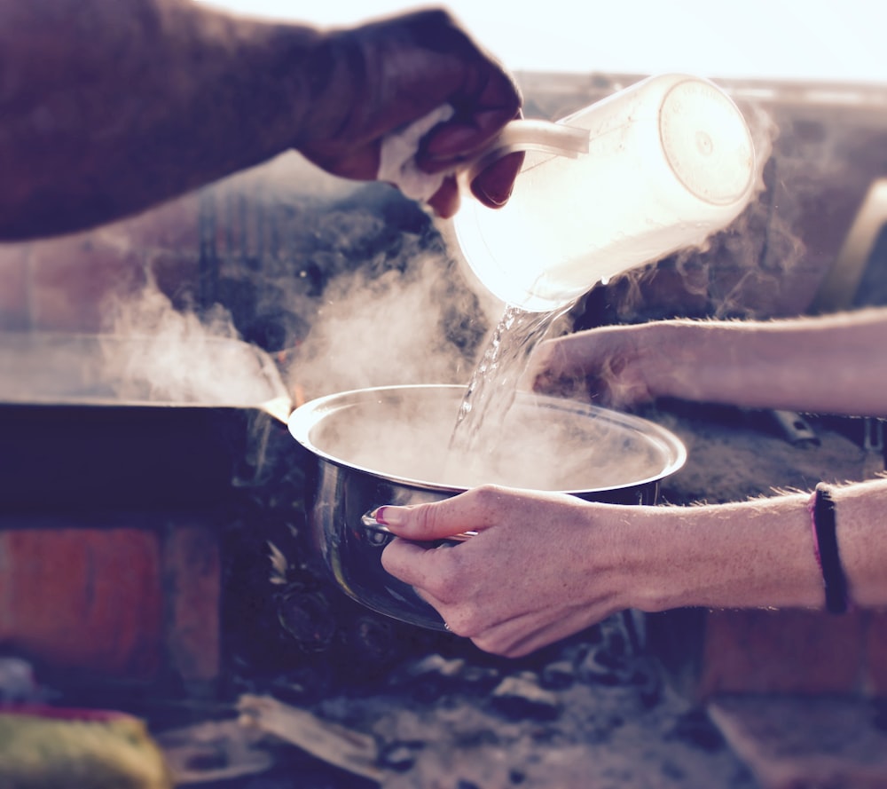 persona che versa acqua su tazza di ceramica bianca