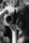 A black and white photograph capturing a person holding a large camera close to their face, with long hair cascading over their shoulders. The person's hand is prominently grasping the lens, and the background is softly blurred, adding focus to the camera and photographer.