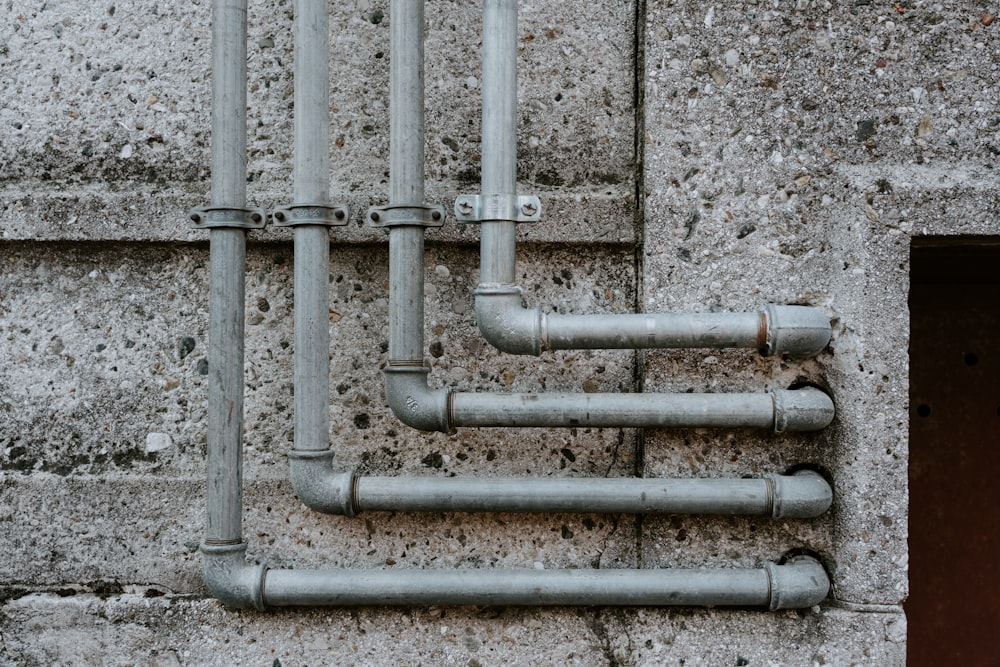 white metal pipe on gray concrete wall