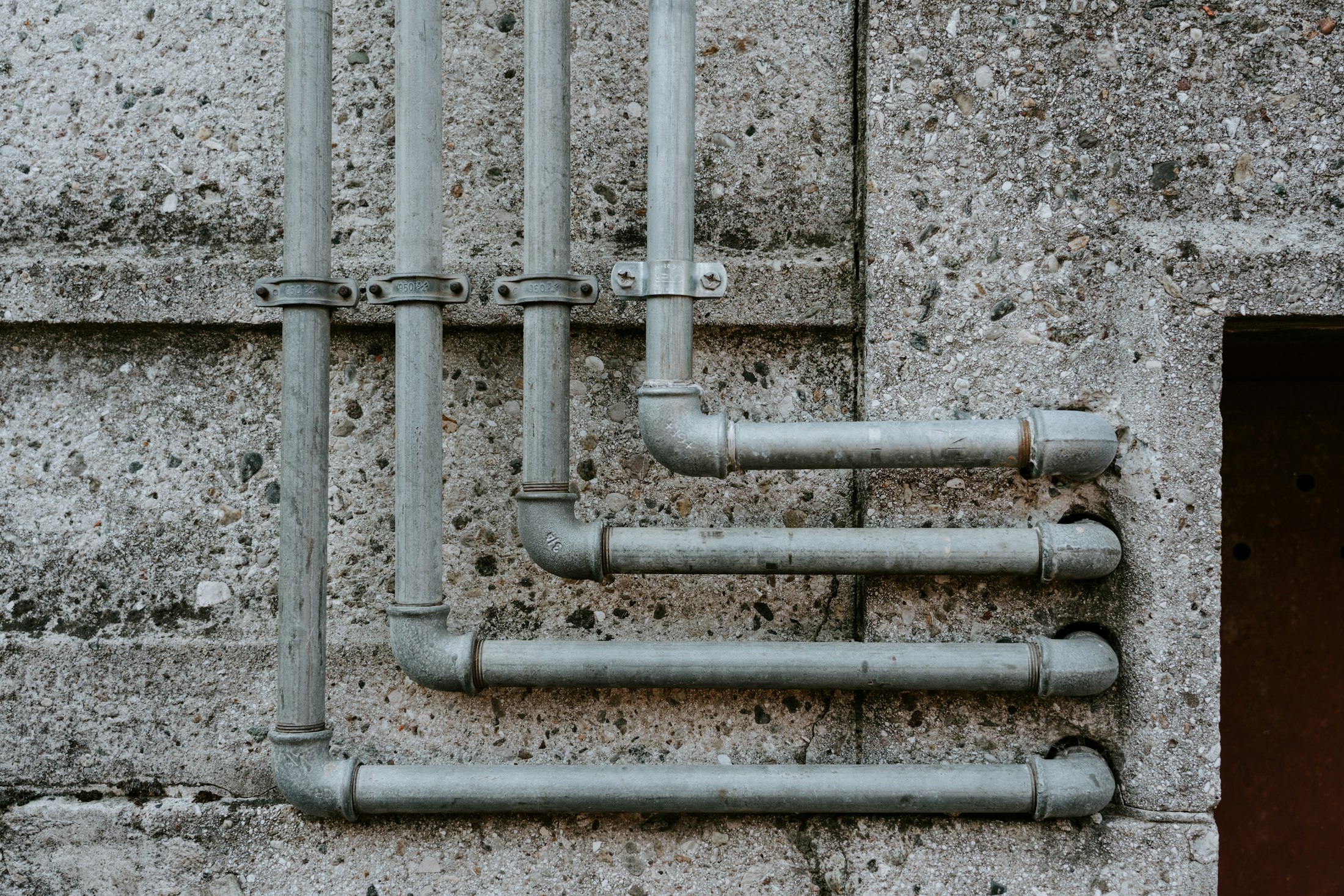 Galvanized pipework across a concrete wall