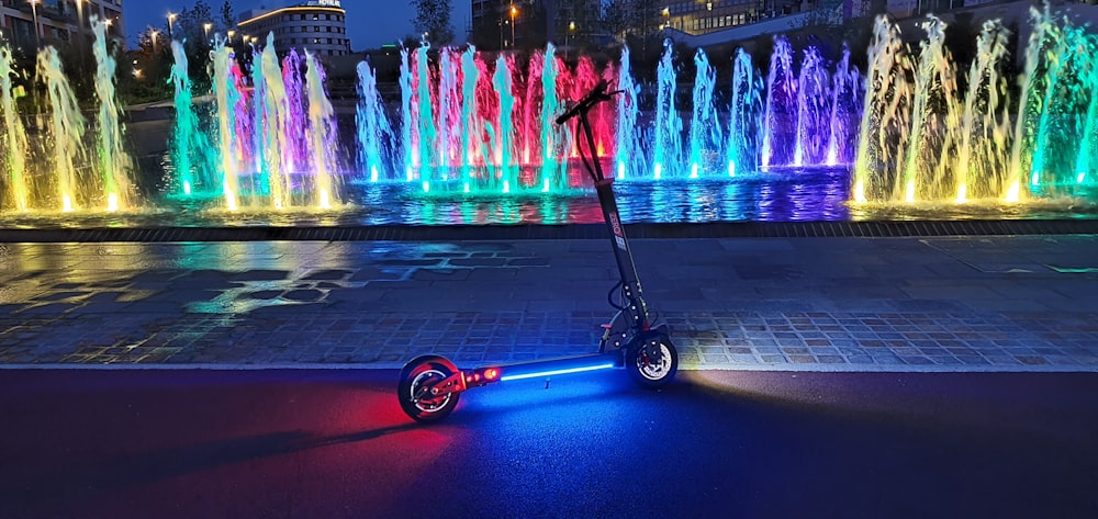 red and black kick scooter near water fountain