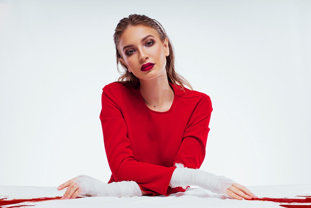 woman in red long sleeve shirt sitting on white textile