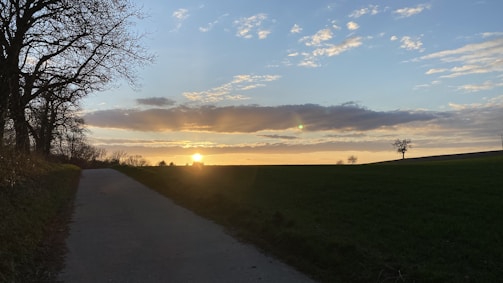 A peaceful countryside road leading to a picturesque lot at sunset