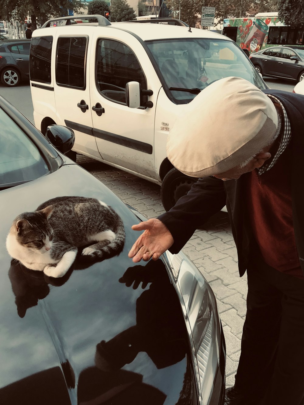 man in brown jacket holding black and white cat
