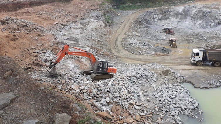 red and black excavator on rocky ground during daytime