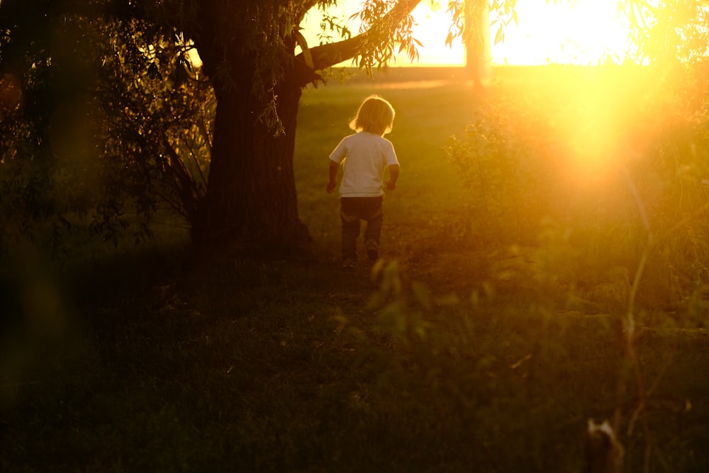 man in white t-shirt standing near tree during daytime