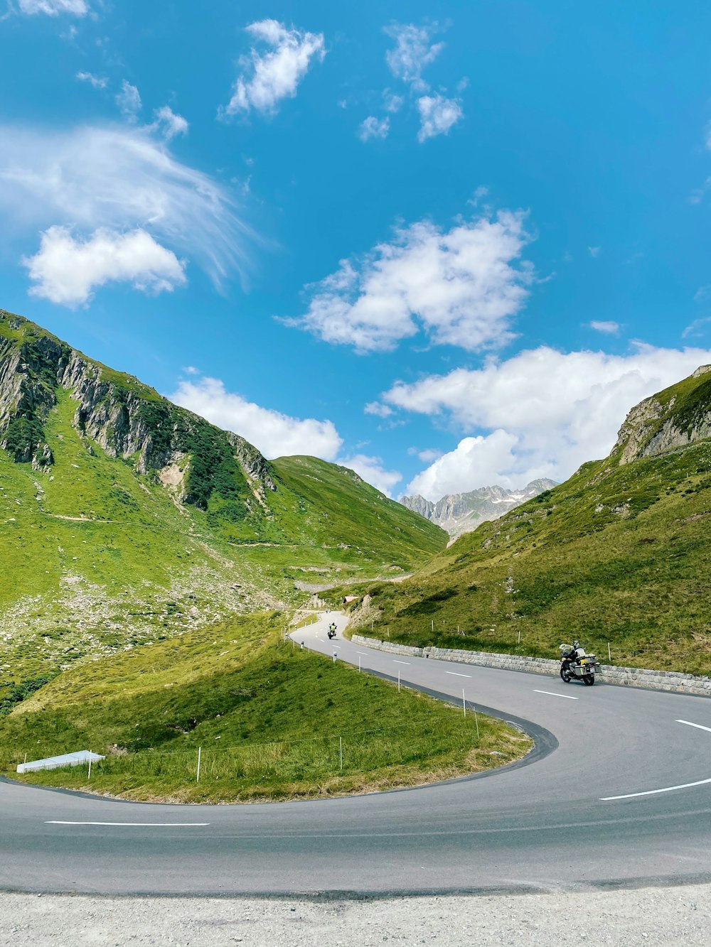 Autos auf der Straße zwischen grünen Bergen unter blauem Himmel tagsüber