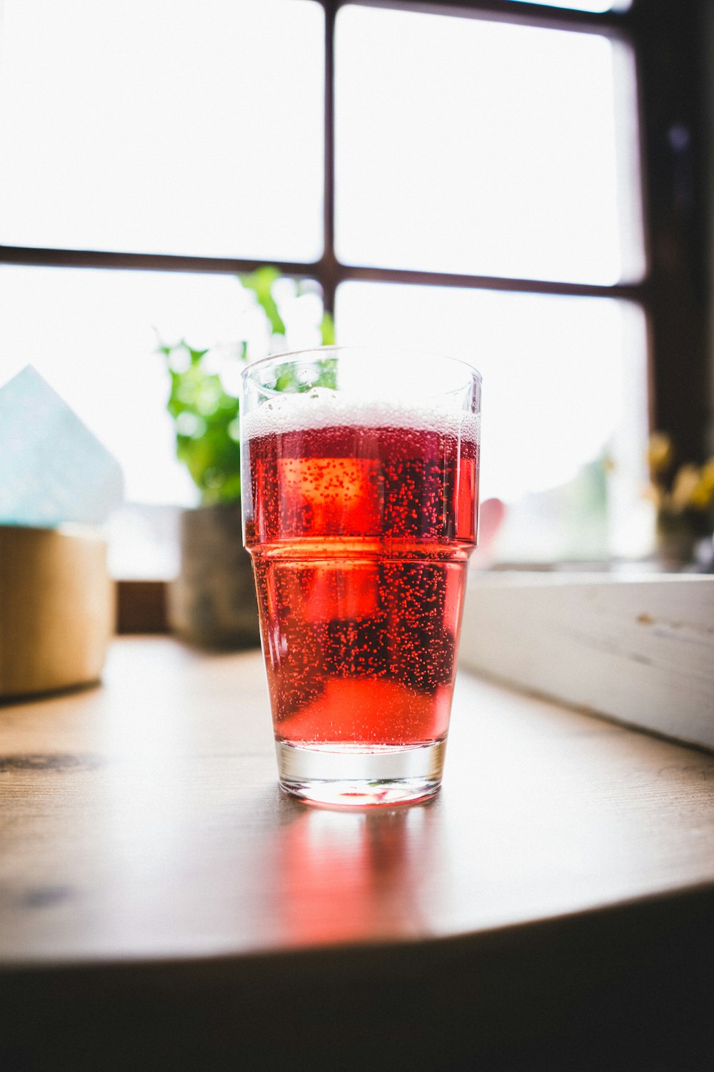 bicchiere trasparente con liquido rosso sul tavolo