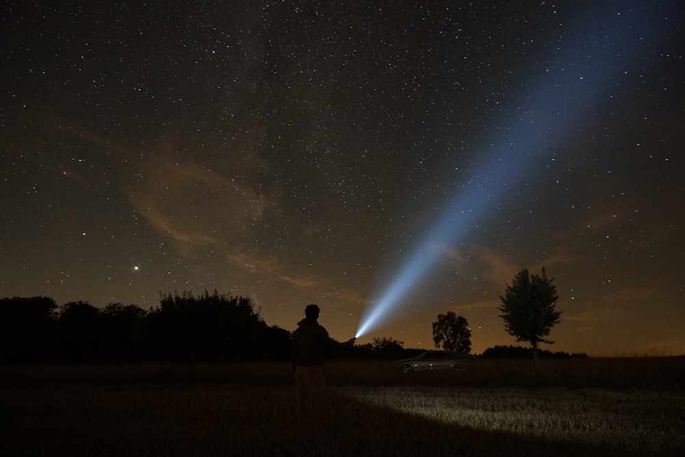 silhouette of person standing on grass field during night time