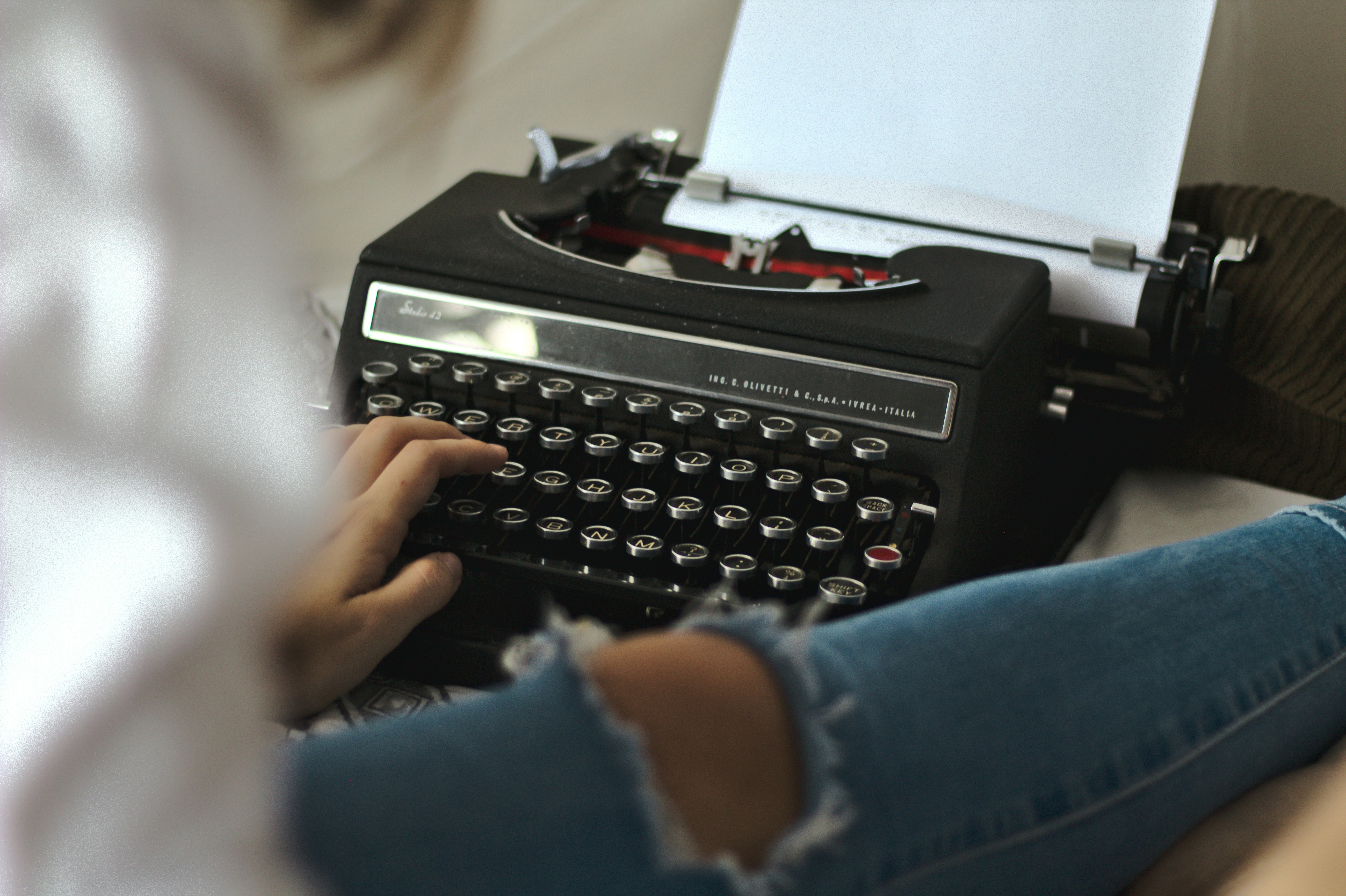 person in blue long sleeve shirt holding black typewriter