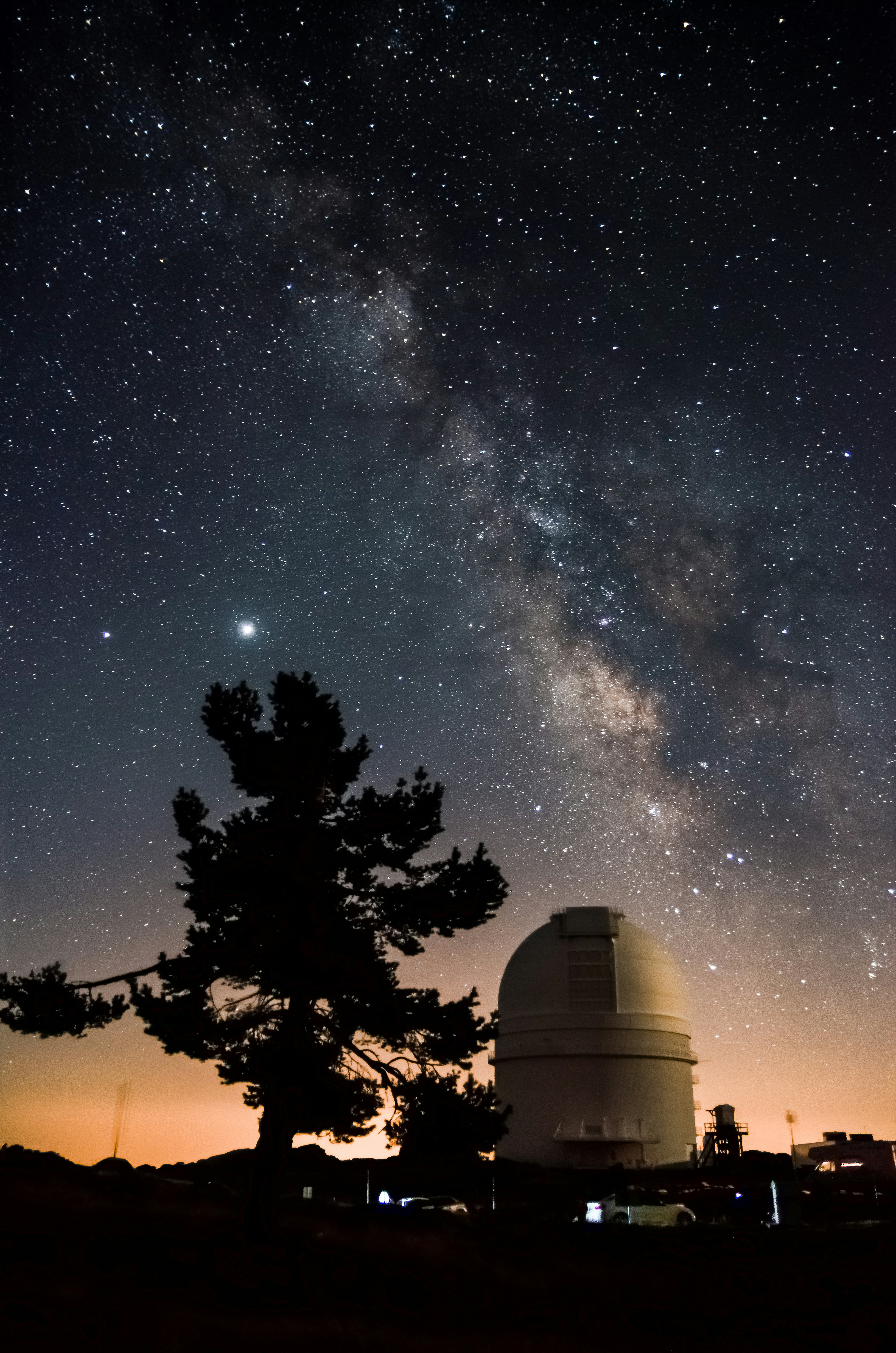 Observatory dome silhouette against deep blue night sky with stars, dramatic low-key lighting, dark environment