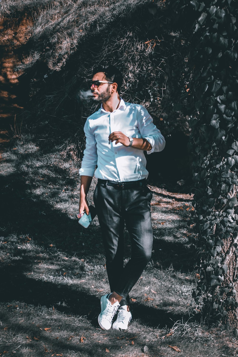 man in white dress shirt and black pants standing beside black and white wall