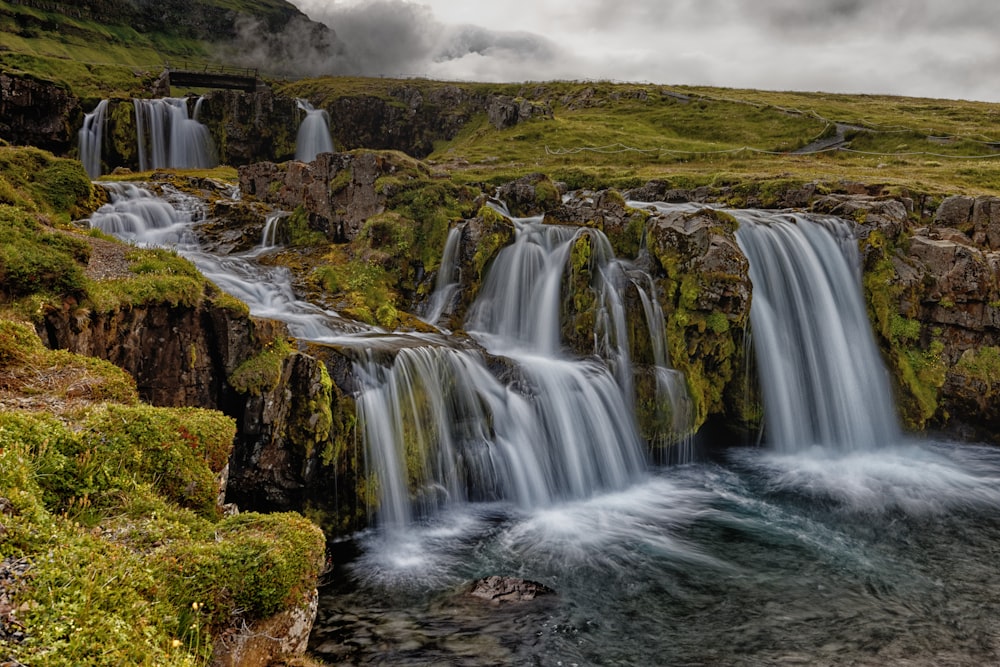 waterfalls in green grass field during daytime