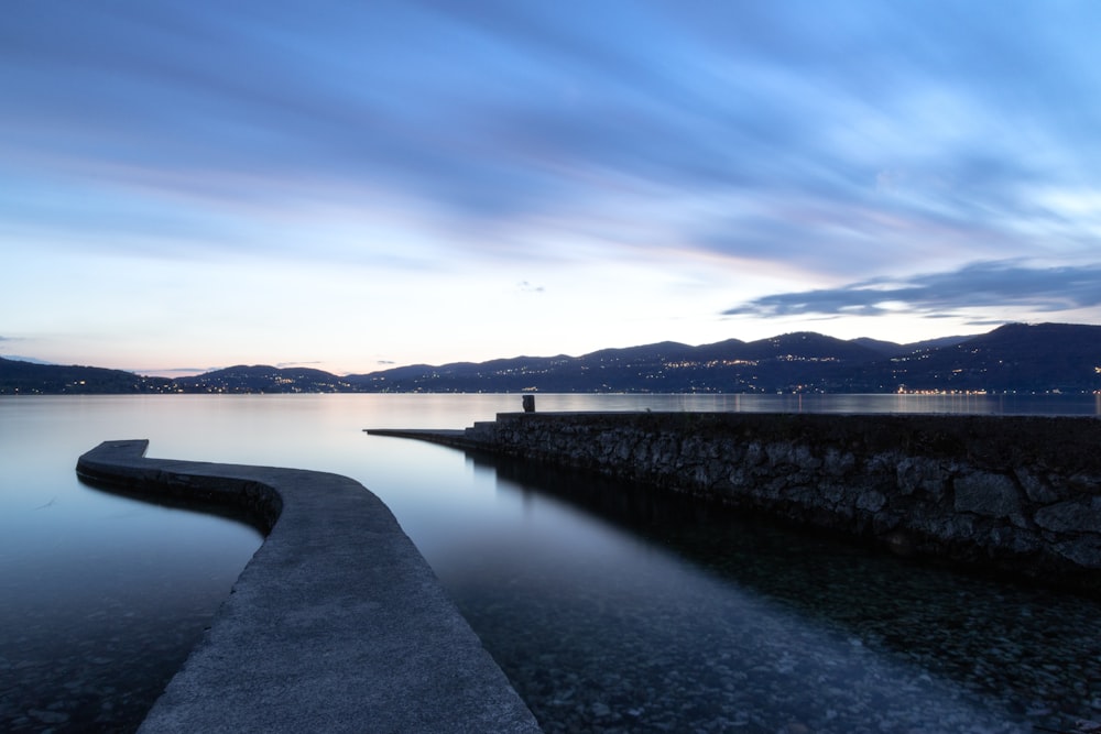 body of water near mountain under blue sky during daytime