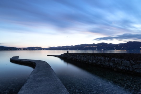 body of water near mountain under blue sky during daytime in Ispra Italy