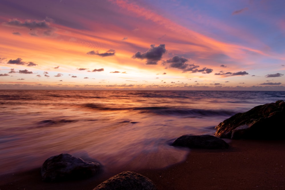 sea waves crashing on shore during sunset