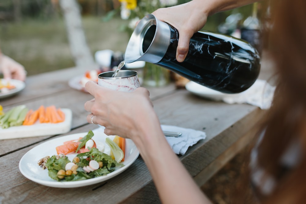 person pouring black liquid on white ceramic bowl