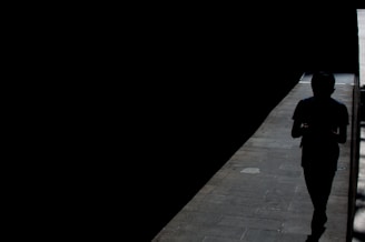 silhouette of person walking on sidewalk during night time