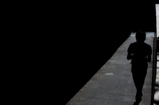 silhouette of person walking on sidewalk during night time