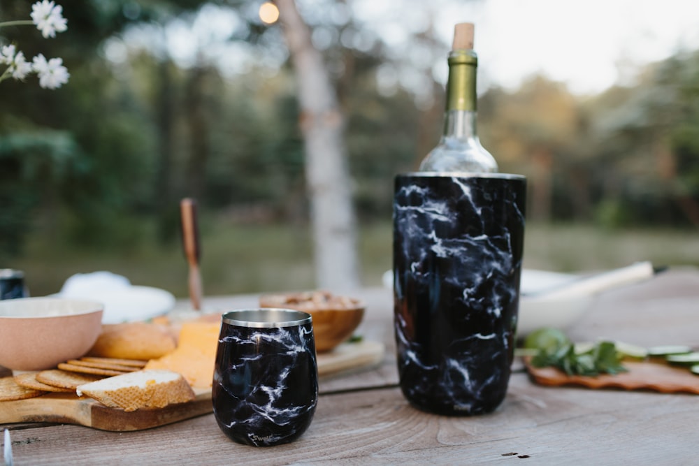 black glass bottle beside bread on brown wooden table