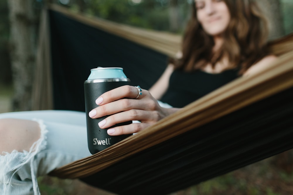 woman in black tank top holding black and silver tumbler