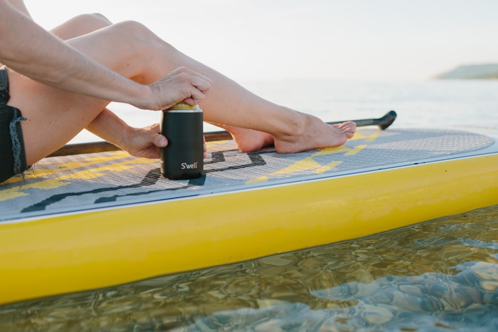 person holding black smartphone on yellow inflatable bed