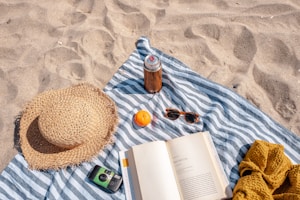 brown glass bottle beside white book on blue and white textile