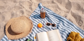 brown glass bottle beside white book on blue and white textile