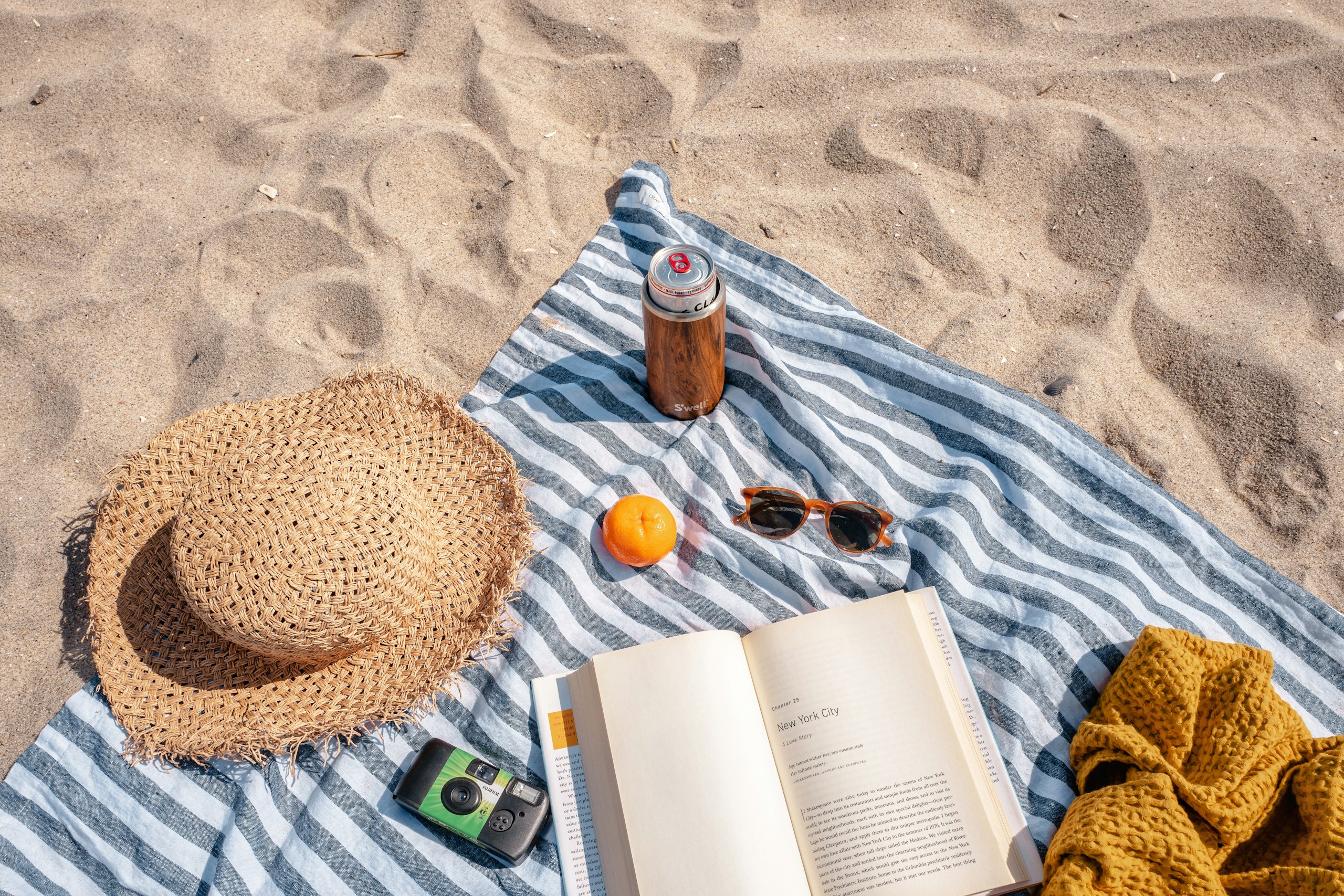 brown glass bottle beside white book on blue and white textile