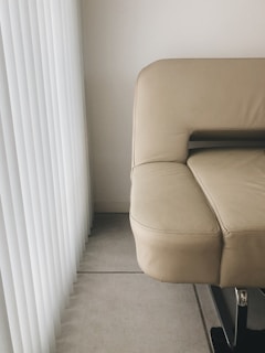 A sleek modern minimalist sofa in a sunlit living room with soft neutral tones.