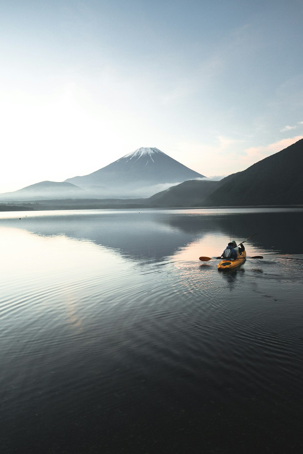 kayak giallo sull'acqua calma vicino alla montagna durante il giorno