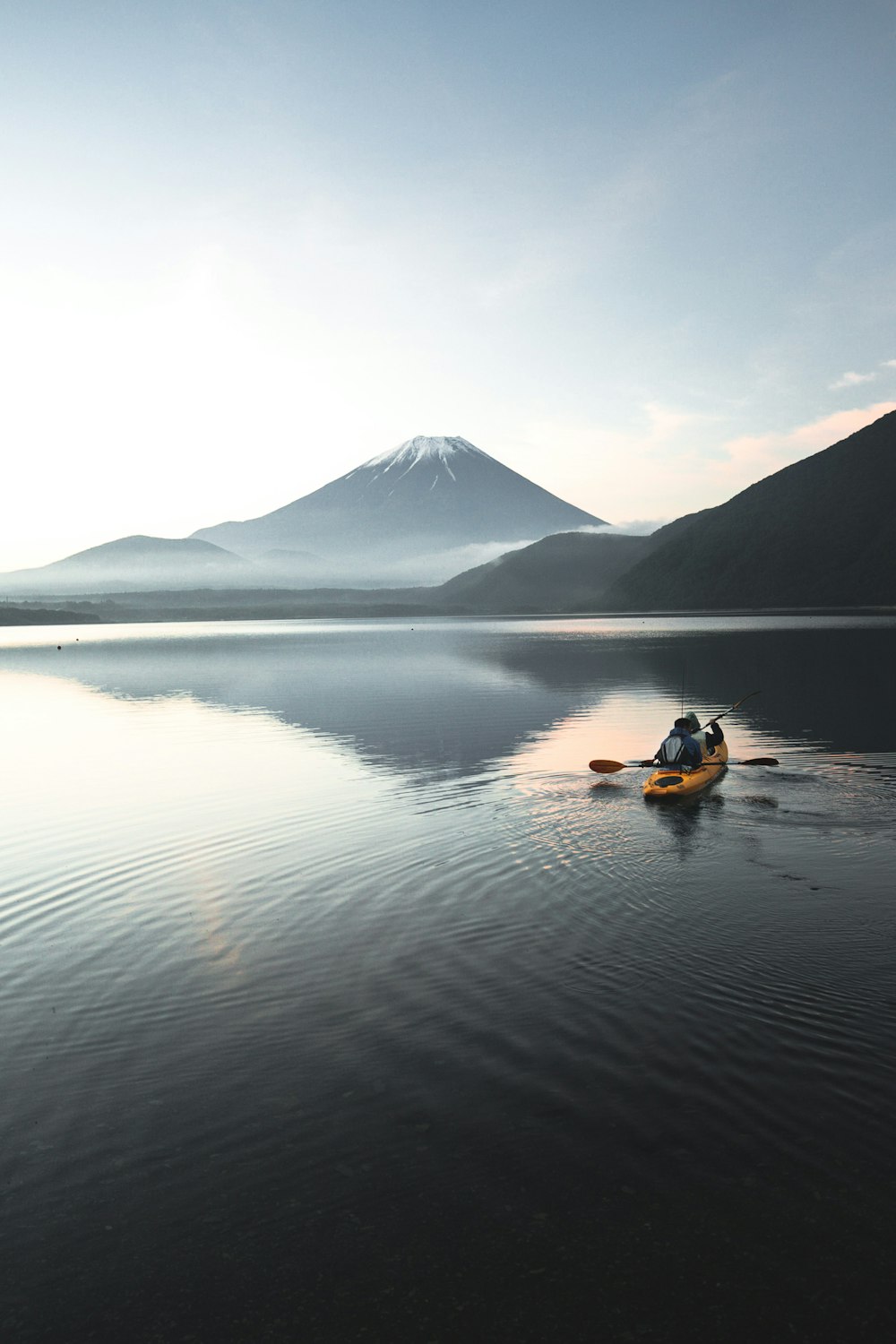 Kayak amarillo en aguas tranquilas cerca de la montaña durante el día