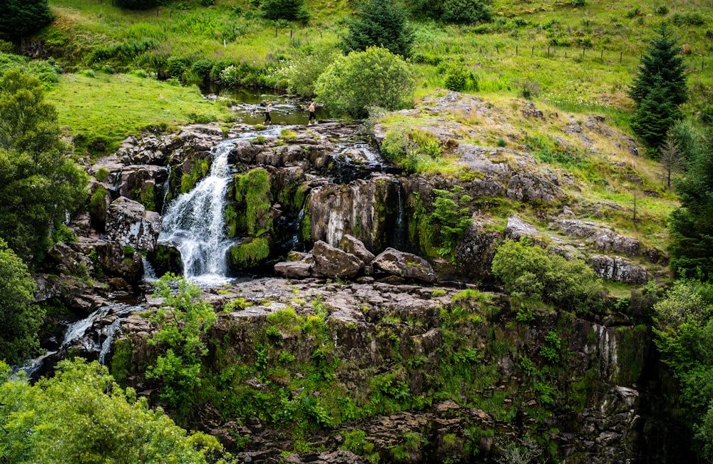 waterfalls on green grass field during daytime