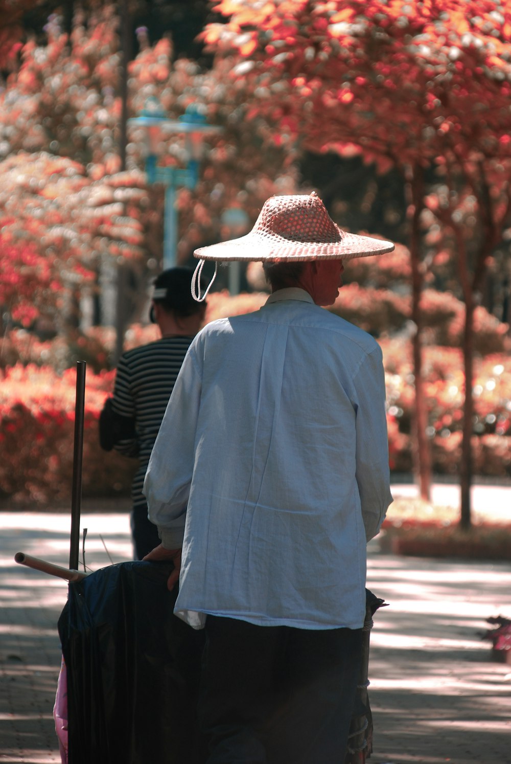 man in blue dress shirt and brown cowboy hat standing on sidewalk during daytime