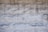 Rough stone wall with rectangular blocks, showing a variety of shades from light gray to beige. The stones have a textured, uneven surface with visible indentations and natural patterns.