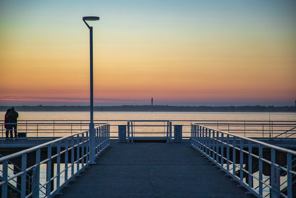 muelle de madera marrón en el mar durante la puesta del sol