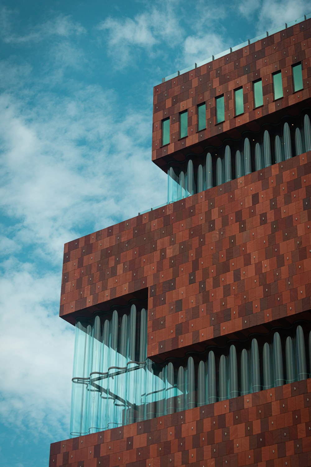 brown and white concrete building under white clouds and blue sky during daytime