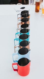 Elegant pourers lined up beside a set of colorful pots and pans