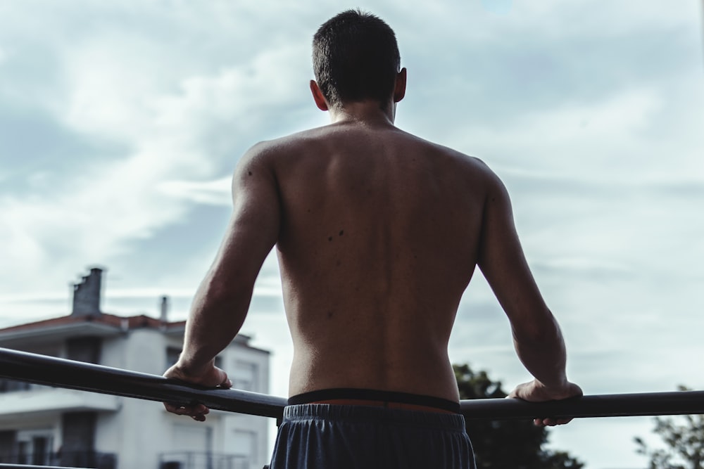 topless man in black shorts holding black metal bar